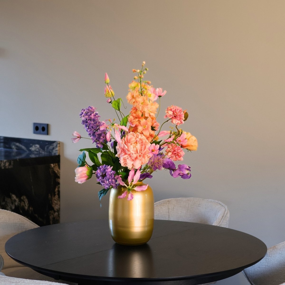 Kunstbloemen boeket met zijden bloemen in prachtige pastelkleuren in een gouden vaas, gepresenteerd op een eettafel