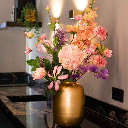 Kunstbloemen boeket met zijden bloemen in prachtige pastelkleuren in een gouden vaas, gepresenteerd in een keuken