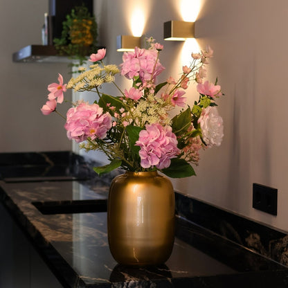 Kunstbloemen boeket met zijden bloemen in wit en roze tinten in een gouden vaas, gepresenteerd in een keuken