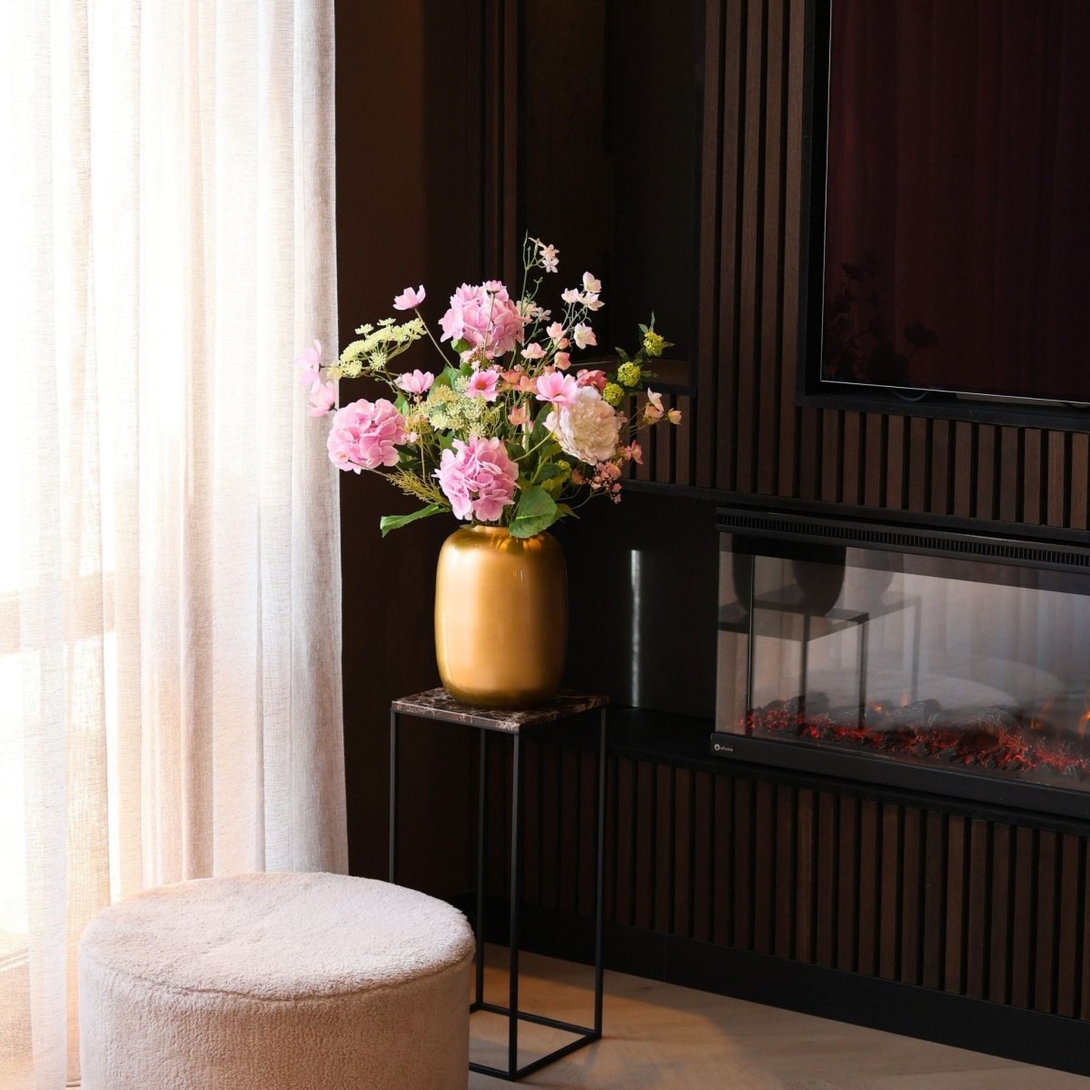 Kunstbloemen boeket met zijden bloemen in wit en roze tinten in een gouden vaas, gepresenteerd in een woonkamer