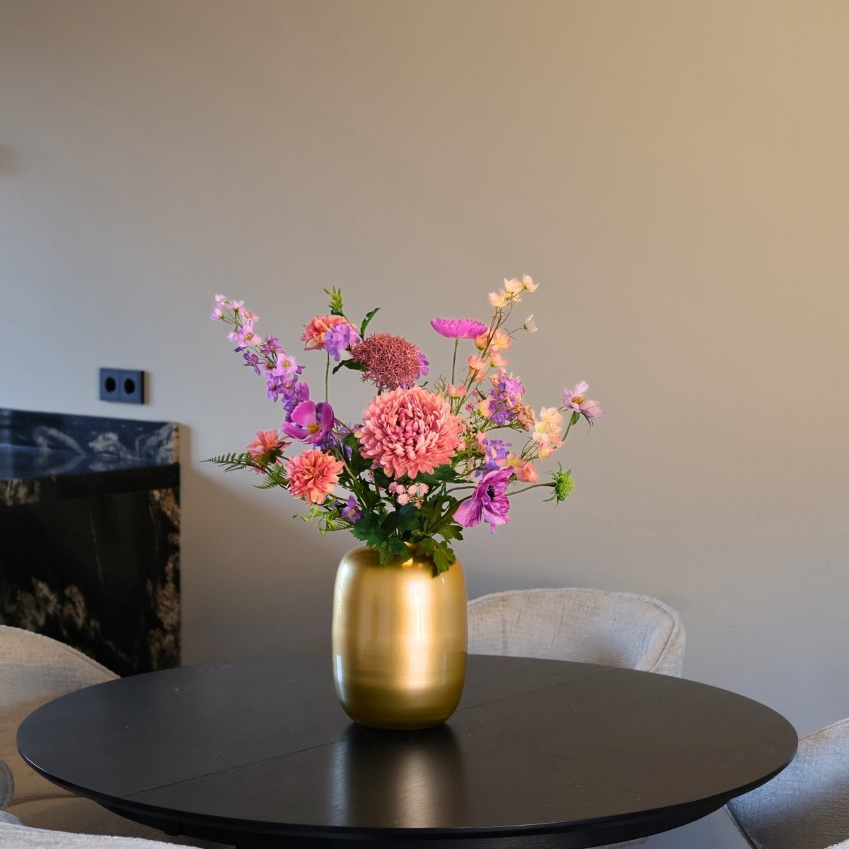 Kunstbloemen boeket met zijden bloemen in paars en lila tinten, in een gouden vaas, gepresenteerd op een eettafel